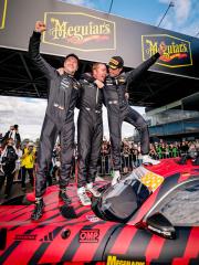 AMG GT racing drivers are standing on top of their car, celebrating their victory