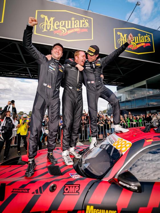 AMG GT racing drivers are standing on top of their car, celebrating their victory