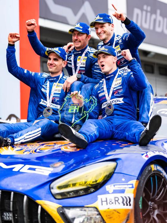 AMG GT racing drivers sit on top of their cars and celebrate their victory